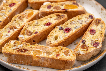 Italian Almond Biscotti biscuits in a rustic home made pottery bowl. Studded with almonds and cranberries, these twice-baked treats are aromatic and inviting. Ideal.