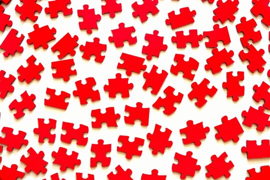 Different red puzzle pieces on white table background