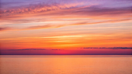 Obraz premium Fiery sunset over a calm ocean with vibrant orange and purple sky water