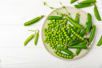 Fresh green pea pods with green peas on a wooden background. Sweet green peas. Green pea beans...