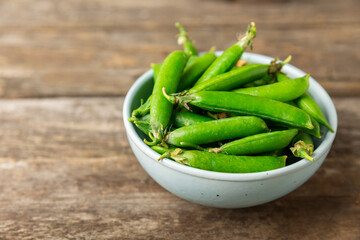 Fresh green pea pods with green peas on a wooden background. Sweet green peas. Green pea beans vegetables. Vegan. healthy vegetable. Copy space