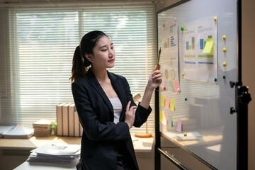 Businesswoman analyzing charts and reports on whiteboard during presentation in office