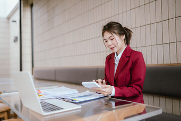 A woman works at a cluttered office desk, reviewing documents and reports. She works with determination and professionalism, managing tasks and official documents in a modern environment.