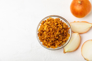 Crispy fried onions in a bowl on a wooden table. Roasted Onions. Seasoning for dishes. Spices....