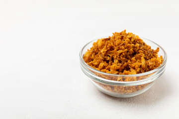 Crispy fried onions in a bowl on a wooden table. Roasted Onions. Seasoning for dishes. Spices. Salad dressing. Space for text. Copy space