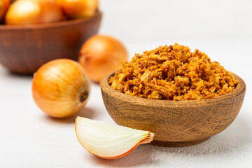 Crispy fried onions in a bowl on a wooden table. Roasted Onions. Seasoning for dishes. Spices....
