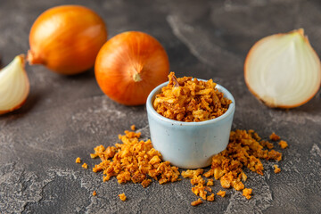 Crispy fried onions in a bowl on a wooden table. Roasted Onions. Seasoning for dishes. Spices....