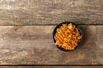 Crispy fried onions in a bowl on a wooden table. Roasted Onions. Seasoning for dishes. Spices....