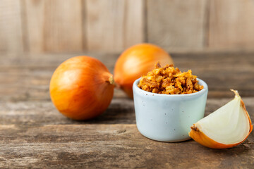 Crispy fried onions in a bowl on a wooden table. Roasted Onions. Seasoning for dishes. Spices....