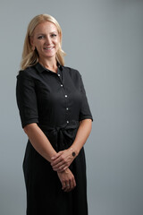 Portrait of a happy business woman isolated on grey background, looking at the camera and smiling.