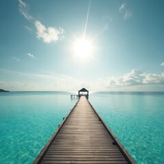 Obraz premium Serene wooden pier extends into calm, turquoise ocean waters under bright sunny sky with scattered clouds. Walkway leads to small covered structure, offering tranquil scene of tropical paradise