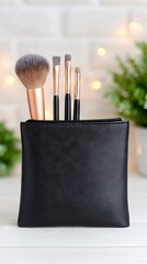 Makeup brushes in a stylish black leather pouch, arranged neatly with soft bristles, set against a blurred background of greenery and warm lights, showcasing beauty tools for professionals