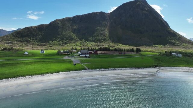 Beautiful summer view at Hov beach in Gimsoy, Lofoten, showing sand, farm and Hoven mountain