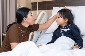 Mother comforting sick child in hospital bed