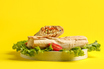 Plate of tasty shawarma with lettuce and tomatoes on yellow background