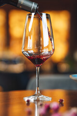 Red wine being poured into glass in elegant restaurant setting