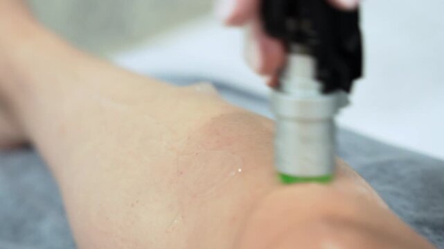 Close up video of professional cosmetologist doing laser hair removal of legs to young woman in beauty salon, Body care epilation treatment.