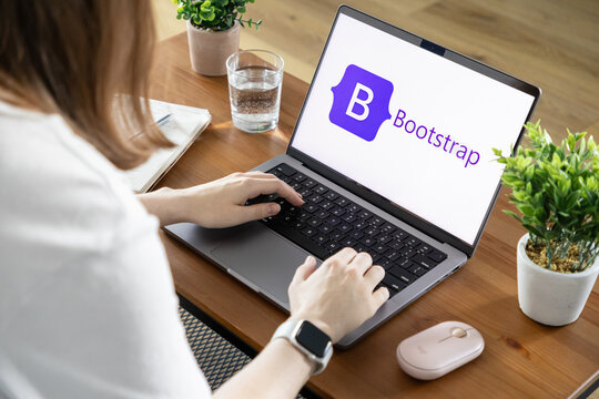 Poznan, Poland - August 23, 2025: Person actively typing on a modern laptop, screen prominently displaying the Bootstrap logo, essential for web development and responsive design