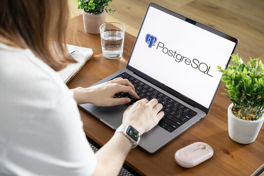 Poznan, Poland - August 23, 2025: PostgreSQL application shown on laptop screen with person typing, symbolizing modern database management, data development, and technology