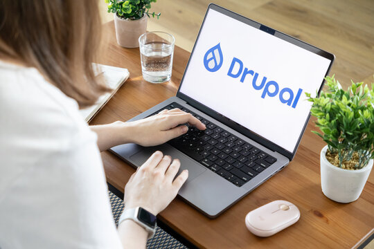 Poznan, Poland - August 23, 2025: Drupal application showcased on a laptop screen, with a person actively using it for web development in a home office setting