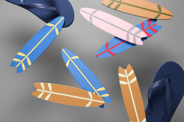 Flying mini surfboards and flip-flops on grey background