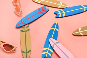 Different mini surfboards and sunglasses on pink background
