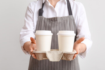 Woman with takeaway paper cups and holder on light background