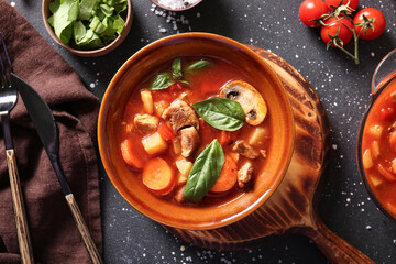 Bowl of tasty beef stew on black background