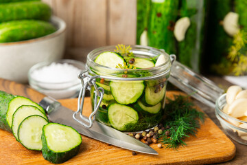 Freshly-salted homemade cucumbers in a jar on a wooden background. pickled cucumbers with dill,garlic and pepper.canned cucumbers.cucumbers and dill.Recipe of homemade preservations.fermented veggies.