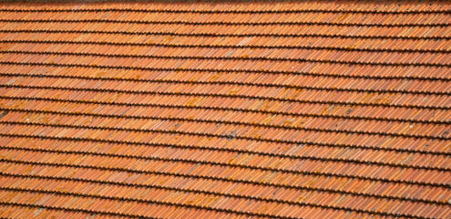 Closeup of old red clay roof tiles showing texture, weathering and natural details