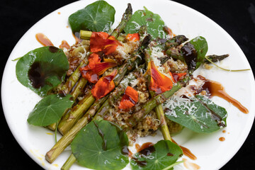 CLOSE UP WHITE PLATE OF HEALTHY COLOURFUL VEGETARIAN SUMMER SALAD WITH EDIBLE PETAL GARNISH 