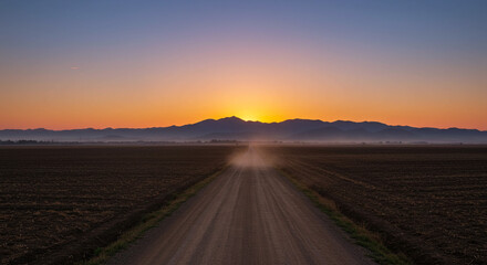 Stunning sunrise paints rural road and mountains in vibrant hues, evoking peace and adventure