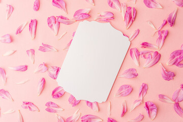 White blank card on pastel pink background surrounded by pink flower petals