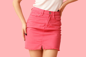Legs of beautiful young woman wearing pink tight mini skirt on pink background