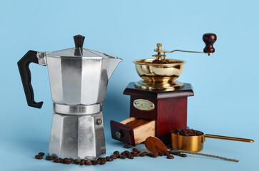Geyser coffee maker with grinder, measuring cup and beans on blue background