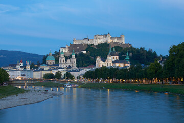 Cityscape of Salzburg at dusk, with the historic Hohensalzburg Fortress on hilltop, Austria