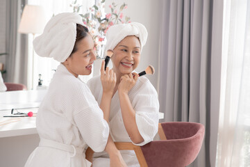 Beauty, skincare, aging, comparison, lifestyle Asian retired mother and daughter in bathrobes sharing bonding moment at vanity table, makeup routine showing generational charm and natural family care