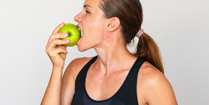 Profile portrait of fit woman eating green apple