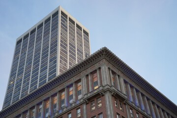 Fototapeta premium Modern skyscraper and historic building in urban setting.