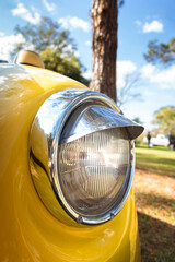 Classic front headlight with chrome trim on a yellow car.
