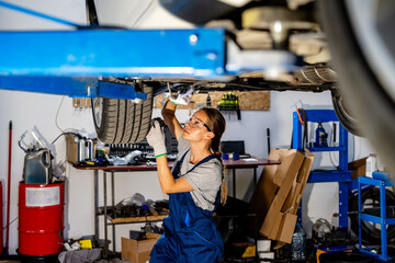 Woman mechanic repairing a car in auto repair shop