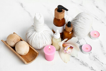 Set of spa supplies with different cosmetic products, herbal bags, orchid flower and burning candles on white background