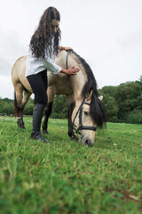 Horse eats green grass. Beautiful girl and beautiful horse walk together in nature. Country life...
