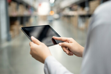 Rear view of Muslim female warehouse worker use digital tablet checking merchandise in warehouse