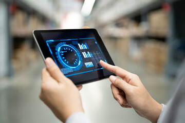 Rear view of Muslim female warehouse worker analyzing business data on tablet PC in warehouse