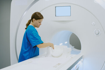 Caucasian young adult woman healthcare worker preparing MRI scanner for patient examination,...