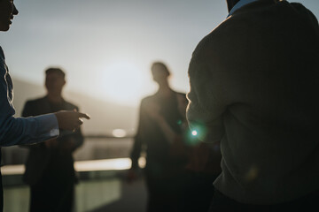 A group of diverse business colleagues enjoying a celebration on a high-rise balcony during sunset, symbolizing unity and success.