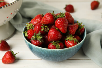 Bowl with sweet fresh strawberries on white wooden background