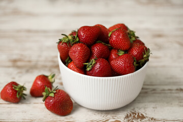 Bowl with sweet fresh strawberries on white wooden background