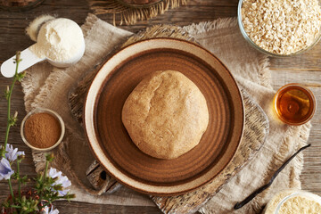 Ball of raw dough made of whey protein powder, ground oat flakes, maple syrup, vanilla and peanut butter - preparation of homemade bars
